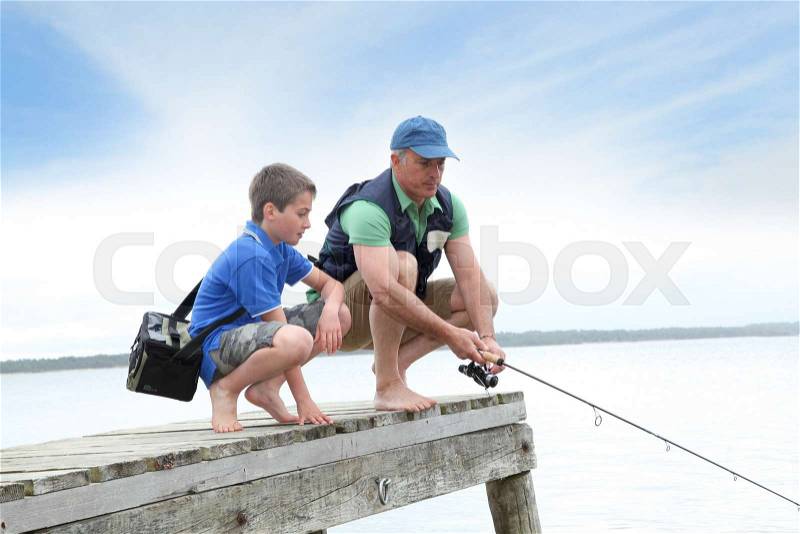Father and son fishing in lake, stock photo
