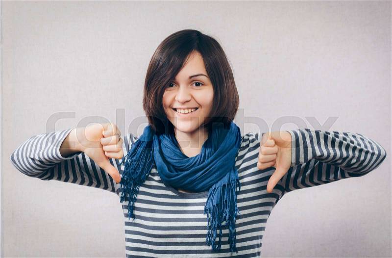 Happy smiling young woman showing thumbs down gesture, stock photo