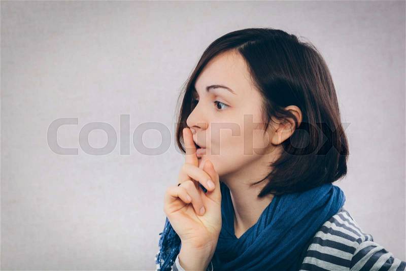 Portrait of casual woman with finger on lips, stock photo
