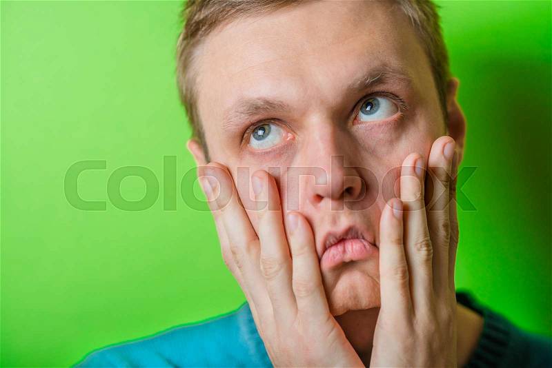 A young man dragging face down with hands, stock photo