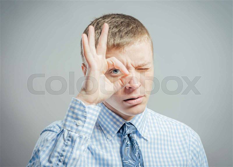 Man with hand over eyes, looking through fingers, stock photo