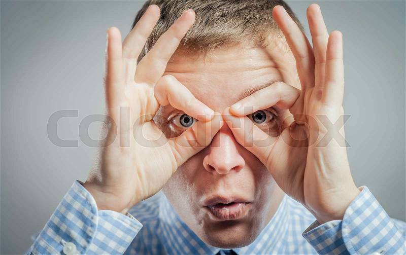 Funny man with hand over eyes, looking through fingers, stock photo