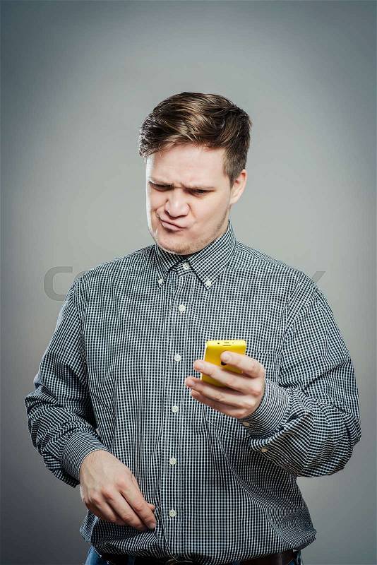 A confused young man looking at mobile phone, stock photo