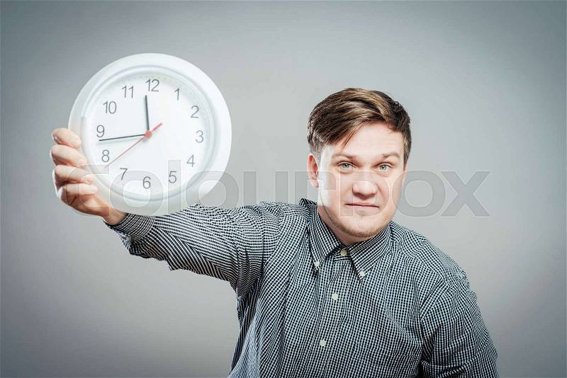 Portrait Of A Young Man Holding A Clock On Gray Background, stock photo