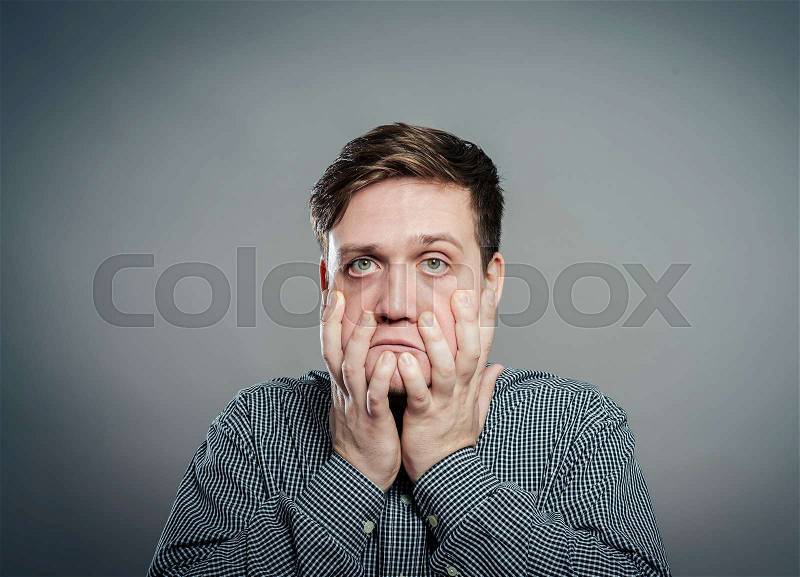 A young man upset with hands on face, stock photo