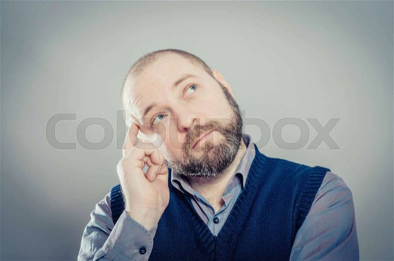 Young man thinks, his finger to his temple, stock photo
