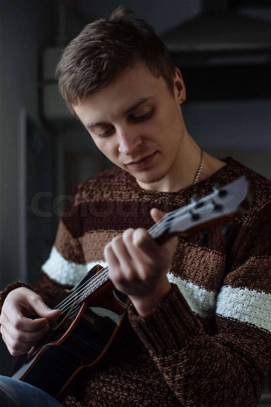 Practicing in playing guitar. Handsome young men playing guitar, stock photo