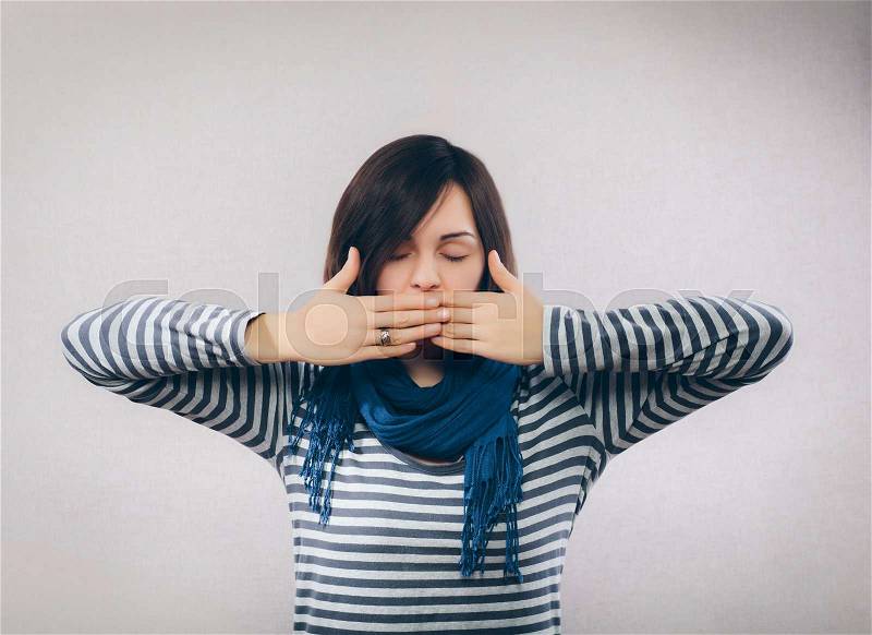 Surprised young woman covering her mouth with hands, stock photo