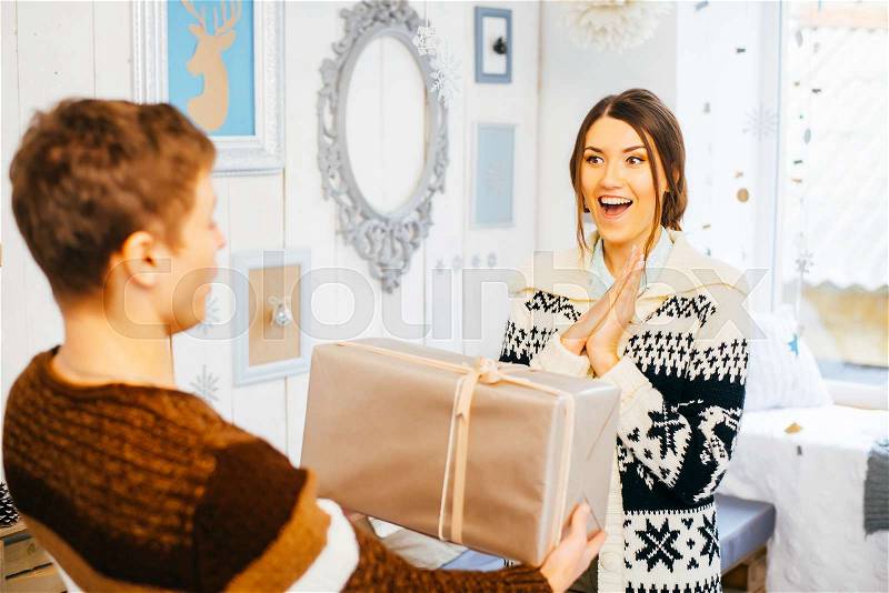 Young man hands a gift box to his girlfriend, stock photo