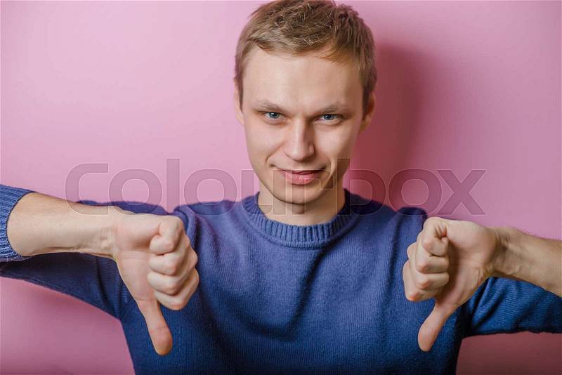 Handsome young man lowered his fist with the thumb down. Close portrait. disgruntled gesture, stock photo