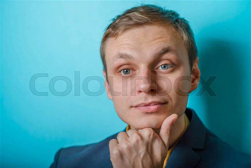 Closeup portrait of a man resting chin on hand, brows raised and daydreaming, staring thoughtfully, stock photo