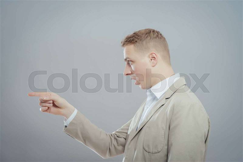 Closeup side view profile portrait man , pointing with finger at someone . Positive human face expression, emotions, feelings, approach, reaction, stock photo