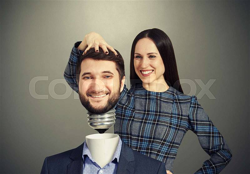 Smiley woman fixing man over dark background, stock photo