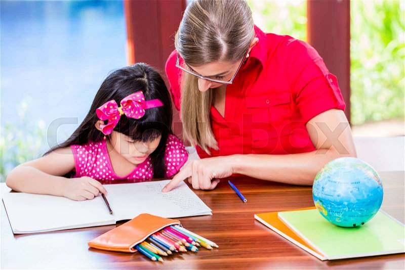 Teacher giving language lessons and doing homework to Chinese child, stock photo