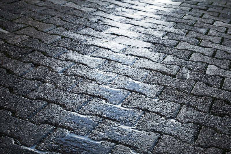 Shining wet cobblestone pavement, abstract urban road background , stock photo