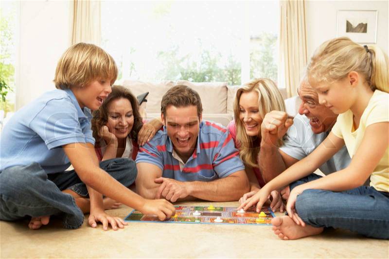 Family Playing Board Game At Home With Grandparents Watching, stock photo