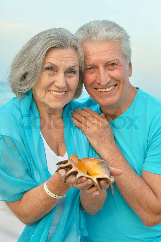 Happy Mature couple enjoy fresh air on beach with seashell, stock photo