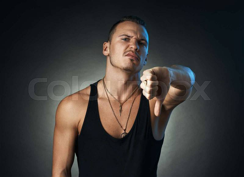 Man showing thumbs down on a black background, stock photo