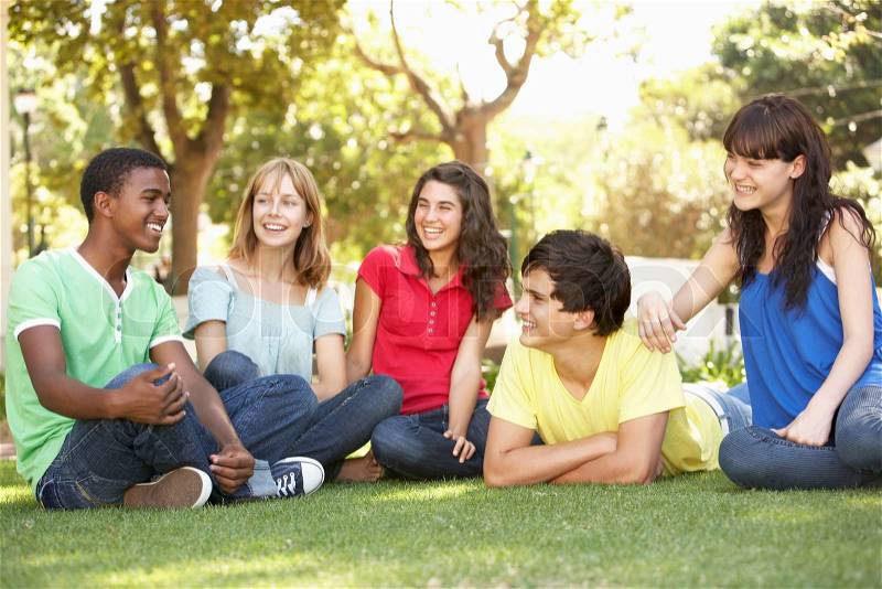 Group Of Teenagers Chatting Together In Park, stock photo