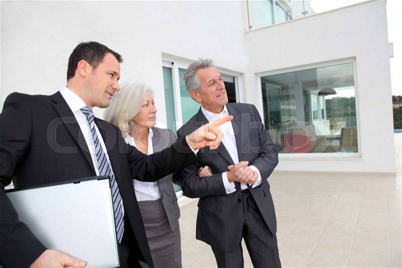 Senior couple visiting luxury villa with real-estate agent, stock photo