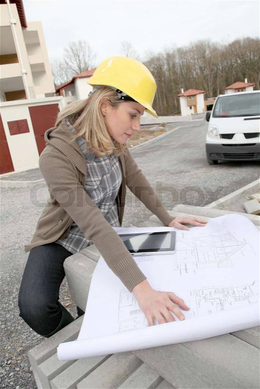 Woman engineer looking at plan on construction site, stock photo