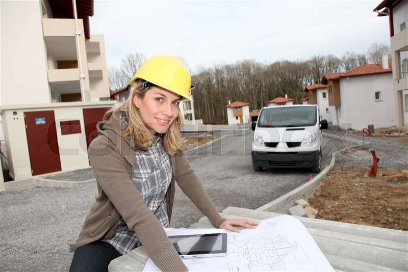 Woman engineer looking at plan on construction site, stock photo