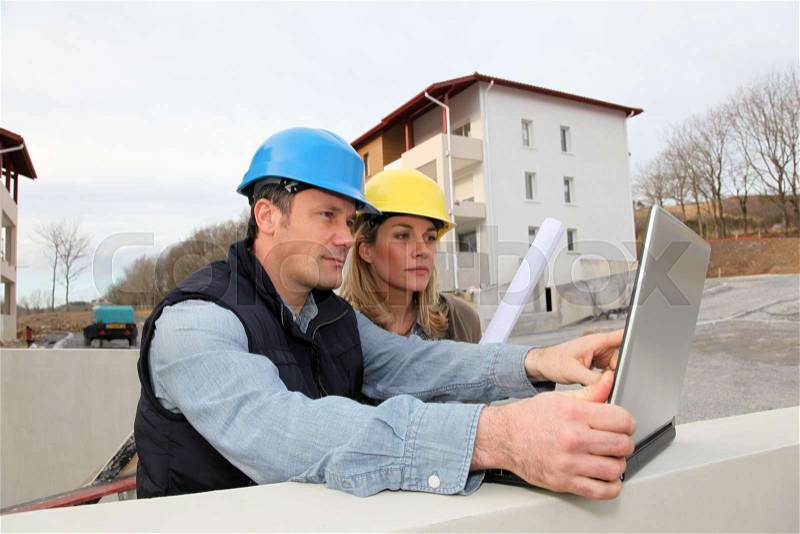 Architect and engineer looking at plan on construction site, stock photo