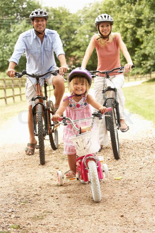 Family Cycling In Countryside Wearing Safety Helmets, stock photo
