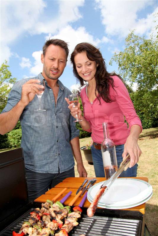 Happy couple cooking meat on barbecue grill, stock photo