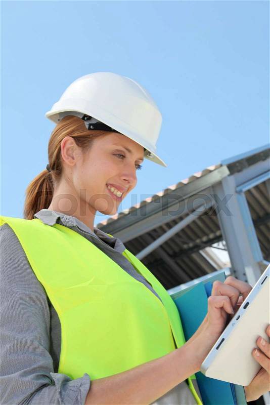 Woman engineer checking building plan on touchpad, stock photo