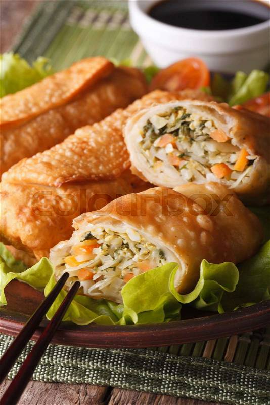 Asian fried spring rolls stuffed with vegetables on a plate and sauce close-up. Vertical\, stock photo