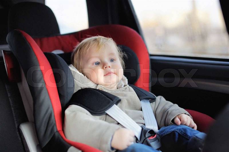 Portrait of toddler boy sitting in car seat, stock photo