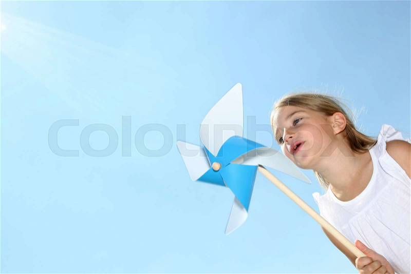 Closeup of little girl blowing blue wind wheel, stock photo