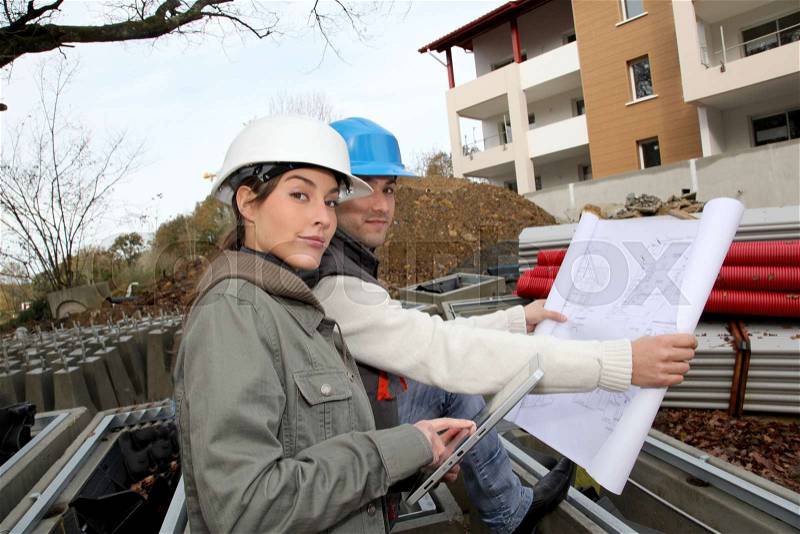 Architect and engineer looking at plan on construction site, stock photo