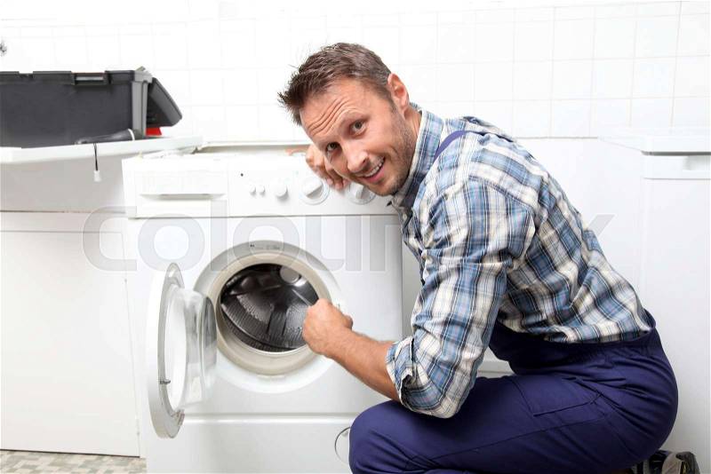 Plumber fixing broken washing machine, stock photo