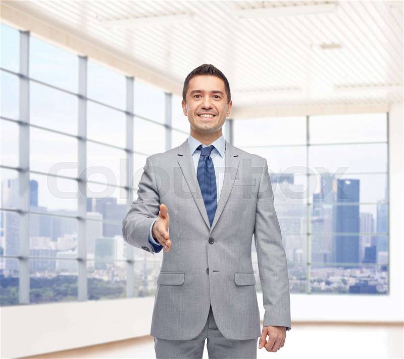 Business people, gesture, partnership, real estate and greeting concept - happy smiling businessman in suit shaking hand over city office window background, stock photo