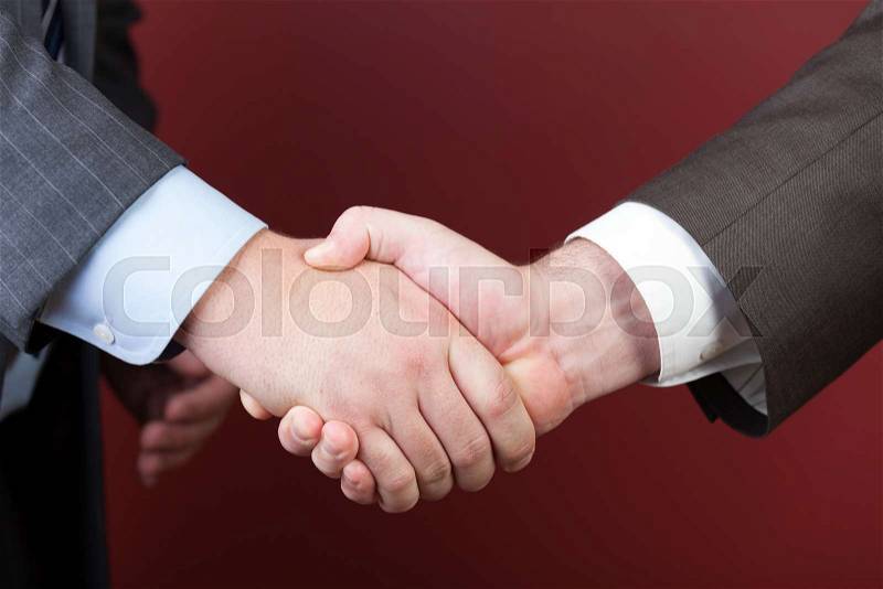 Business negotiations illustrated with a close up of a handshake between two men, stock photo