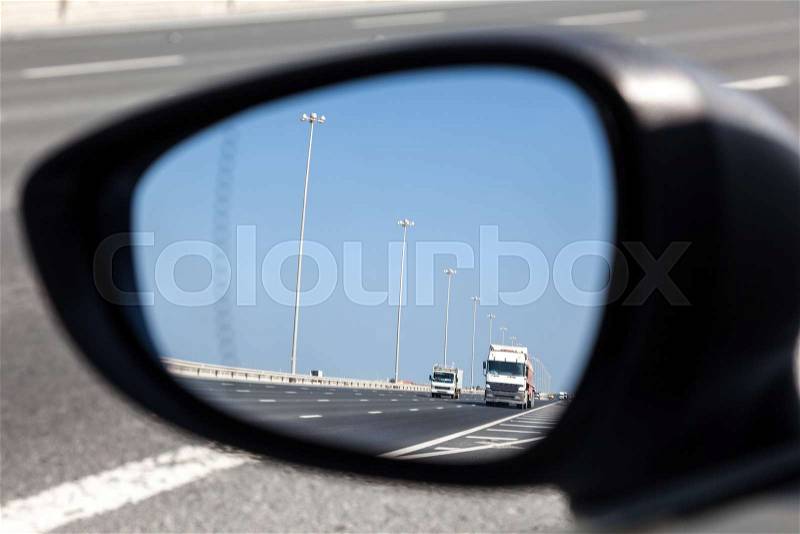 Trucks on highway in the rear-view mirror, stock photo