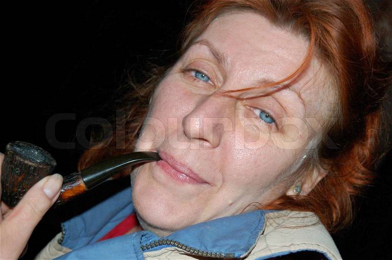 Face of mature lady resting outdoor at late evening with old pipe, stock photo