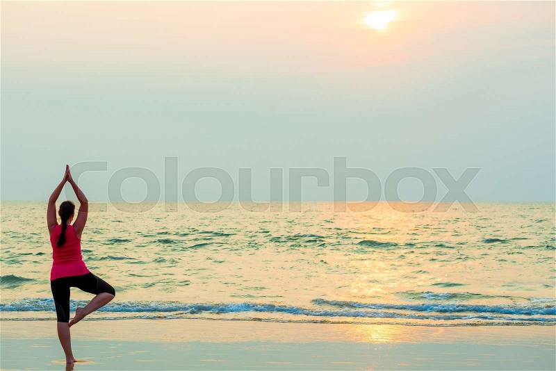 Slender girl balancing on one leg. Yoga on the beach, stock photo