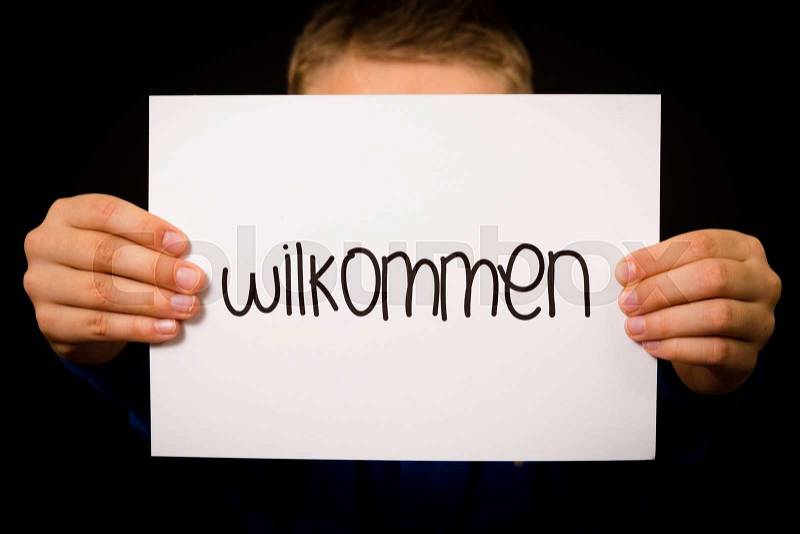 Studio shot of child holding a sign with German word Wilkommen - Welcome, stock photo