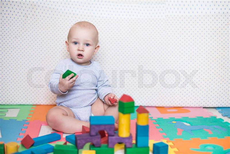 Child plays with toy blocks in the nursery, stock photo