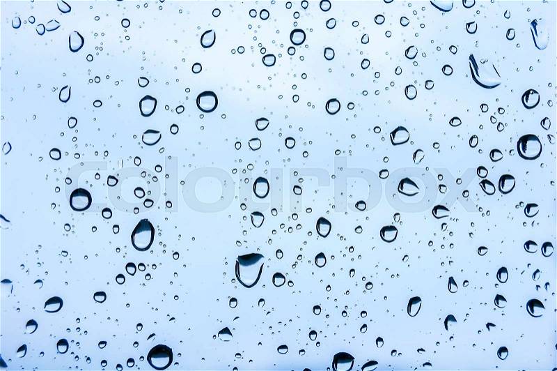 Raindrops on a window pane on the background of a stormy sky, stock photo
