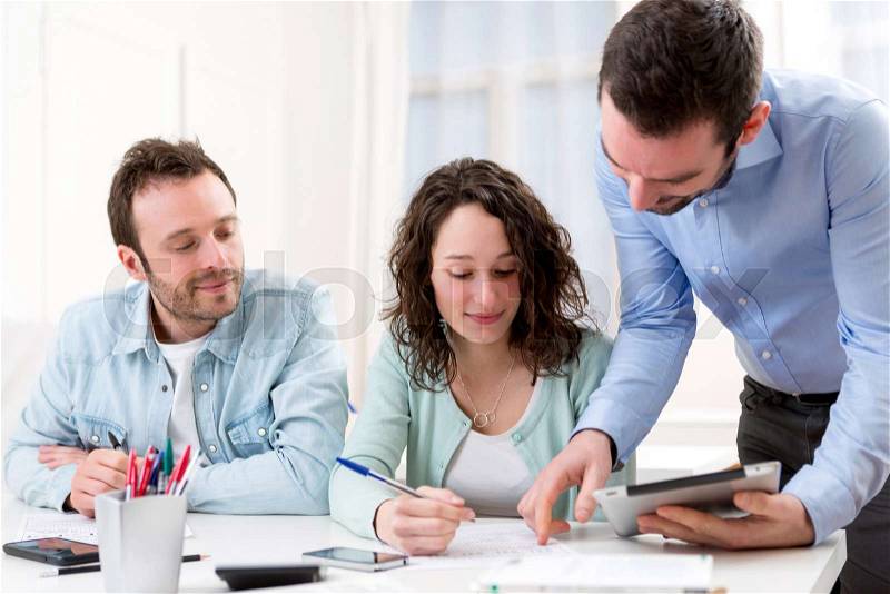View of Two interns working together assisted by their course supervisor, stock photo