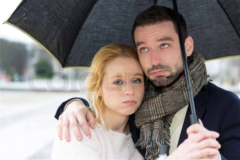 View of a Portrait of a young couple on holidays under the rain, stock photo