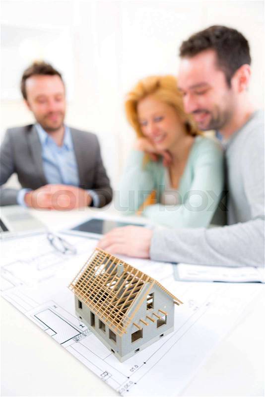 View of a Miniature house in a desk of real estate agent with couple, stock photo