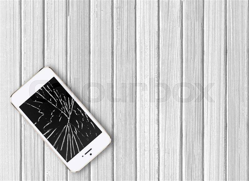 Modern broken mobile phone on white wooden background, stock photo