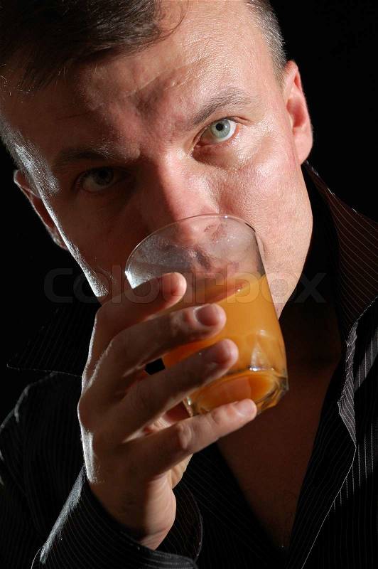 Close-up studio portrait of a middle-aged handsome man drinking juice, stock photo