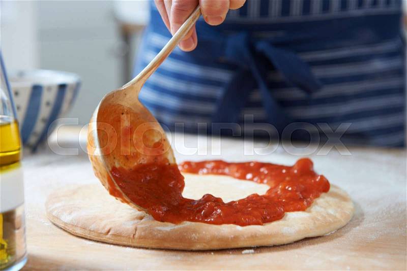 Close Up Of Adding Tomato Sauce To Pizza Base, stock photo