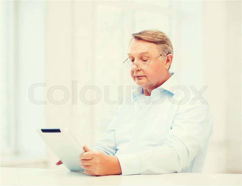 Business, office, oldness, school and education concept - old man wearing eyeglasses with tablet computer at home, stock photo